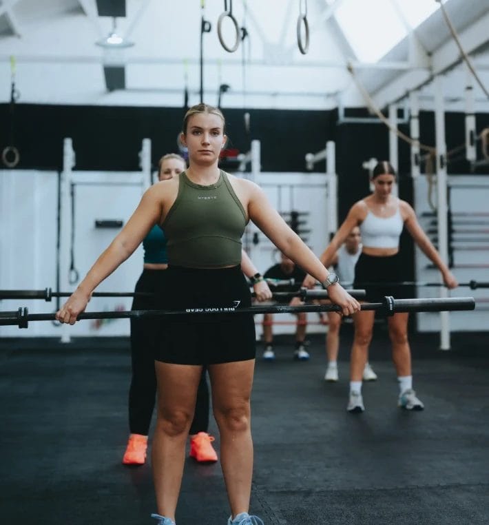 Group of women preparing for barbell strength training in a gym