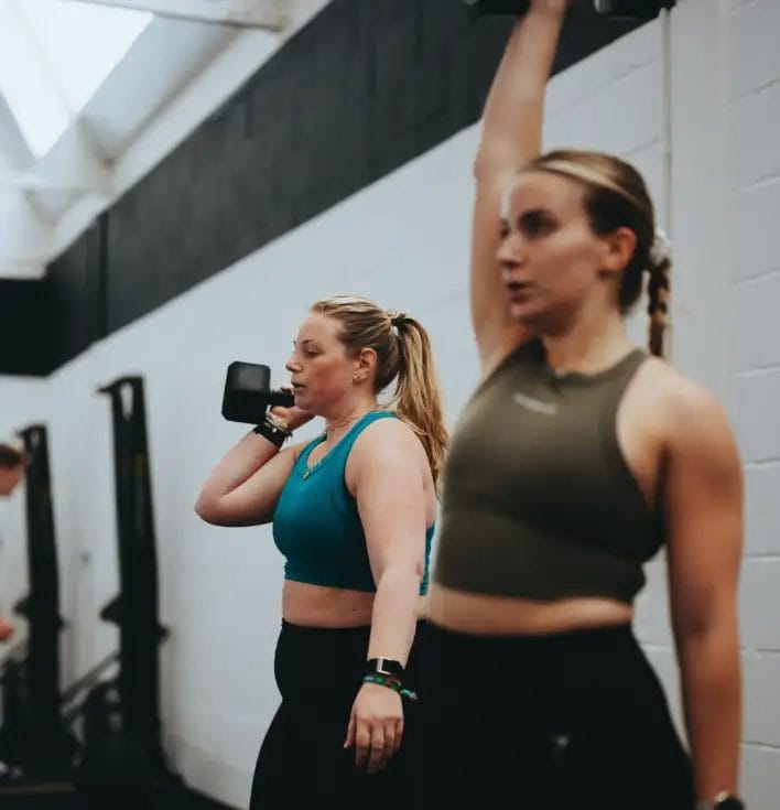 Women performing kettlebell and dumbbell exercises in a gym