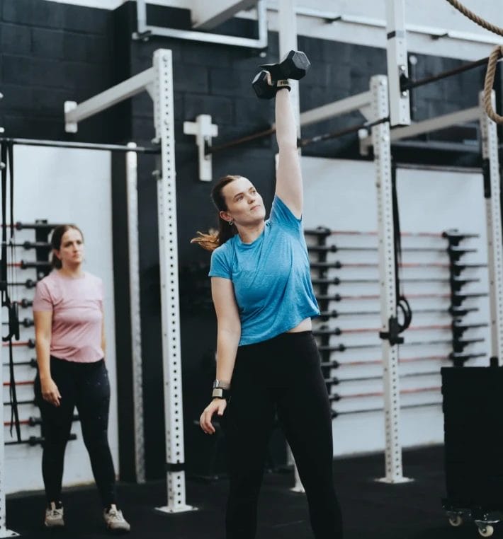 Woman performing a single-arm dumbbell press during a workout